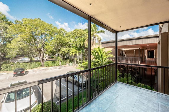 View from a balcony showing parking area and surrounding trees.
