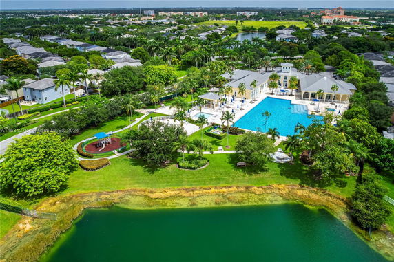 Wide-angle view of a recreational area with a swimming pool, surrounded by greenery and residential buildings.