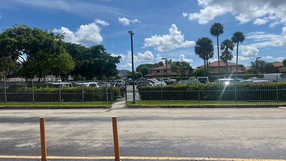 Outdoor parking area with multiple cars and trees in the background.