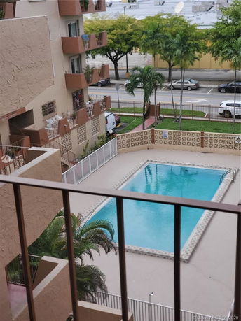 View from a balcony overlooking a swimming pool and nearby building.