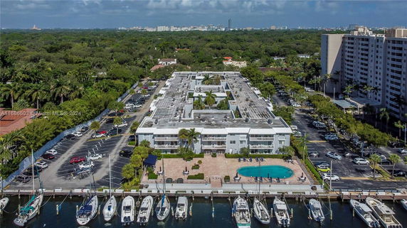 Aerial view of a multi-story building complex with boats docked by the waterfront.