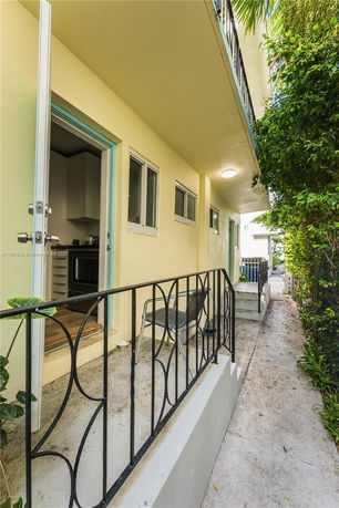 Side view of a building entrance with an open door and small porch area.
