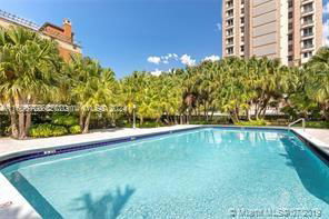 Outdoor swimming pool with trees and a tall building in the background.