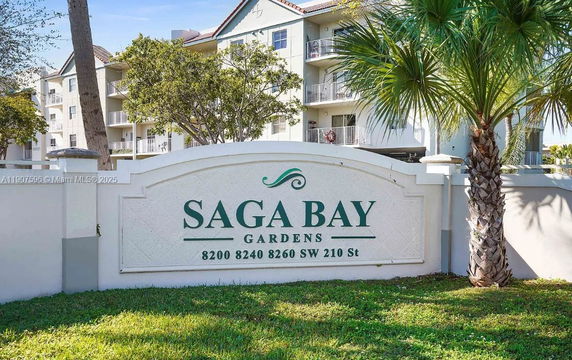 Front view of a building complex with balconies behind a decorative entrance sign.