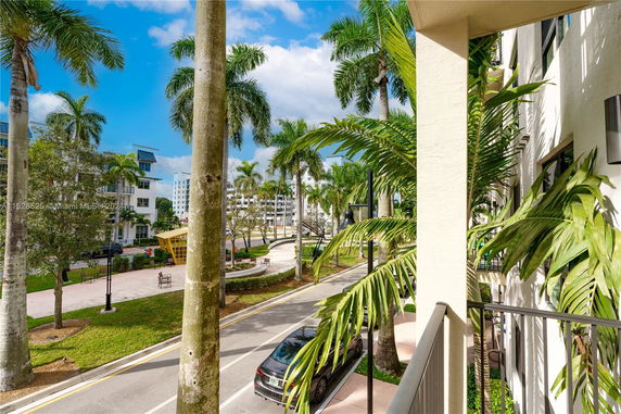 View of street and palm trees from a balcony.