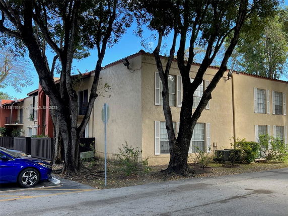 Front view of a two-story apartment building with multiple windows and adjacent parking area.