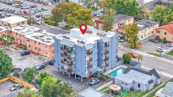 Aerial view of a multi-story building with a flat rooftop featuring multiple air conditioning units.
