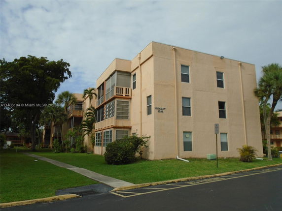 Front view of a multi-story residential building with beige exterior and balconies.