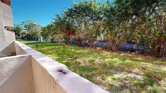 View from a building looking out onto a grassy area with trees and a fence.