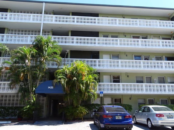 Front view of a multi-story apartment building with white lattice balconies and an entrance canopy marked 1425.