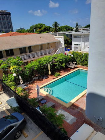 Outdoor swimming pool area with surrounding greenery and lawn chairs.