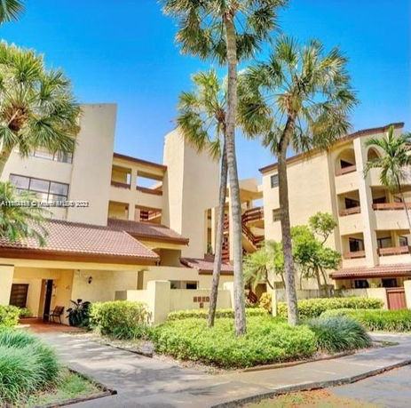 Front view of a multi-story building with balconies and palm trees.