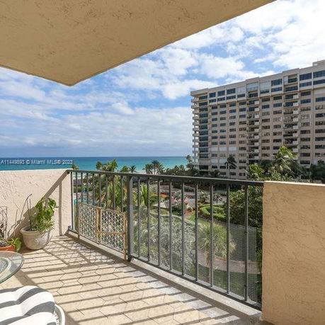 View from a balcony overlooking an ocean and a tall apartment building.
