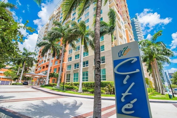 Front view of a multi-story residential building with palm trees.
