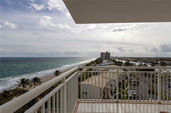 Panoramic view of the ocean and cityscape from a balcony.