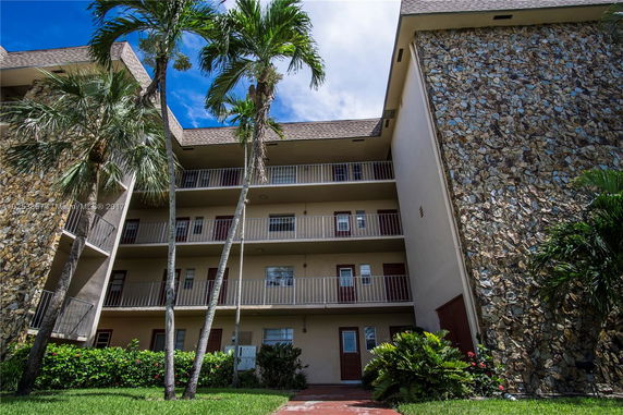 Front view of a multi-story residential building with stone accents and balconies.