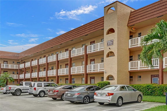 Front view of a multi-story building with balconies and parking spaces.