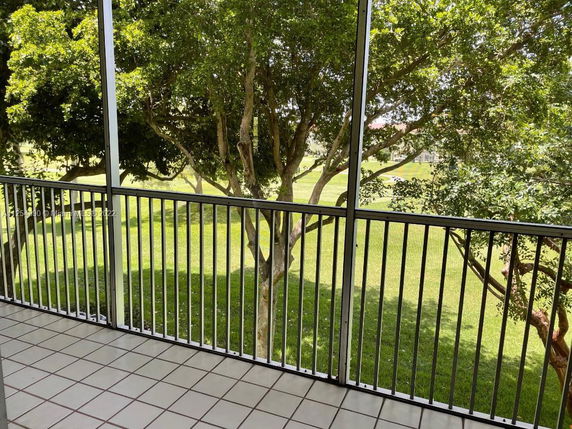View from a balcony overlooking a grassy area and trees.