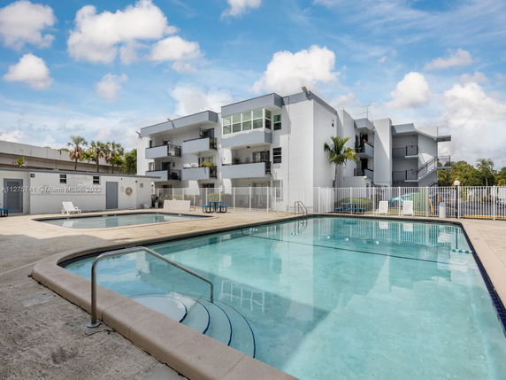 Outdoor view of a building with a swimming pool in front.