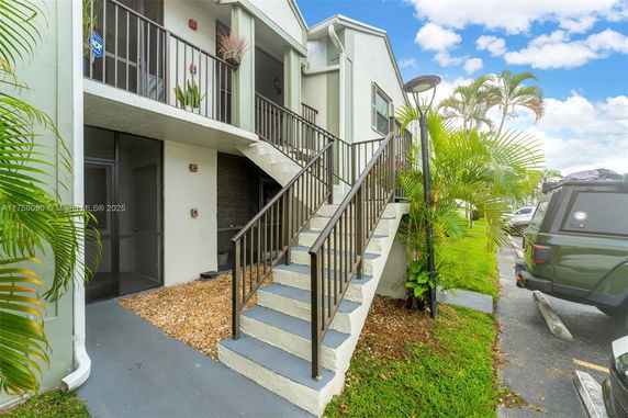 Front view of a two-story building with outdoor staircase and balcony.