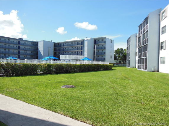 Front view of multi-story residential buildings with balconies and green lawn.