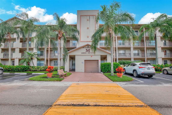 Front view of a multi-story apartment building with a central entrance and balconies.