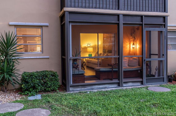Front view of a house with screened patio area and interior lighting visible.