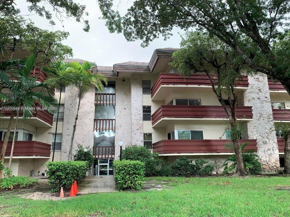 Front view of a multi-story residential building with balconies and exterior stonework.