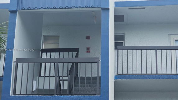 Front view of a two-story building with blue and white colors and a balcony.