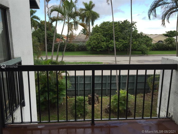 View from a balcony overlooking a street lined with trees and houses.