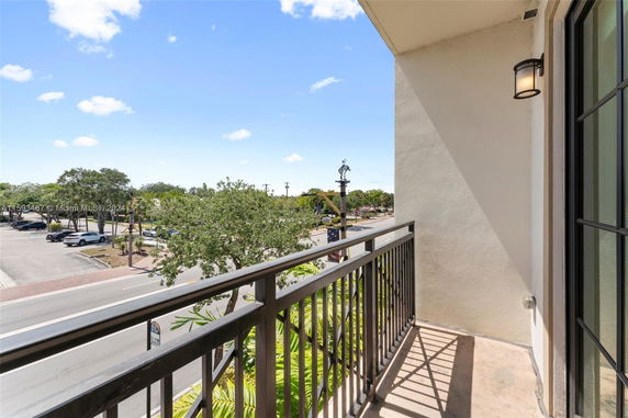 View from a balcony overlooking a street and parking area.