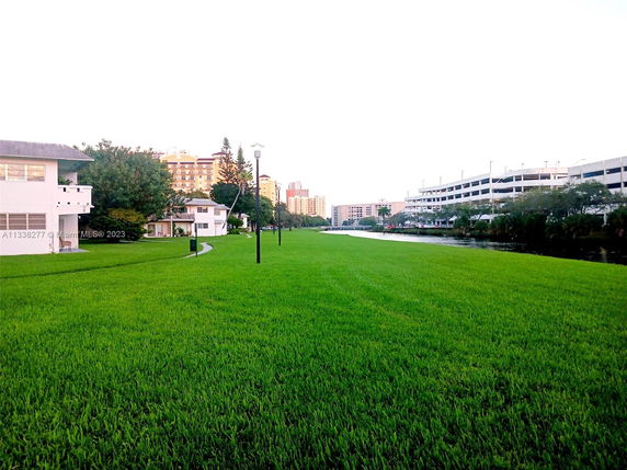 View of buildings and green lawn with a water body nearby.