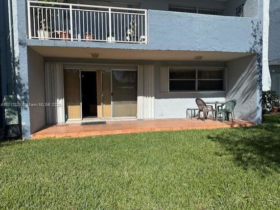 Front view of a two-story building with balconies and patio doors on the ground floor.