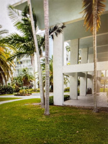 Ground-level view of a building with tall columns and palm trees.