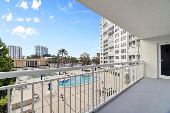 View from a balcony overlooking a pool area and nearby buildings.