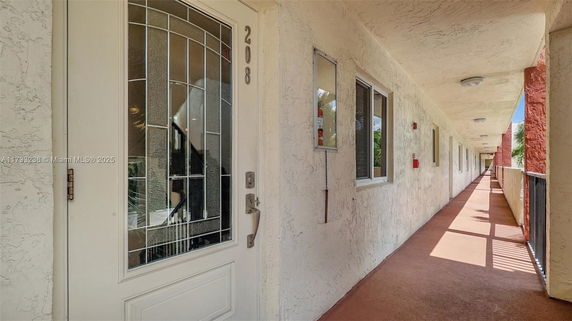 Corridor view of an apartment entrance with white door and windows.