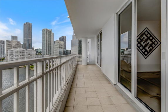 Panoramic view from a high-rise balcony overlooking a cityscape with tall buildings.