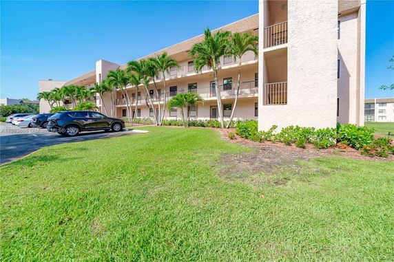Front view of a multi-story building with balconies and parking area.