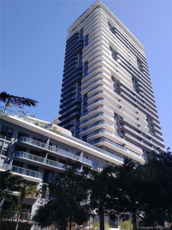 Front view of a modern high-rise residential building with multiple balconies.