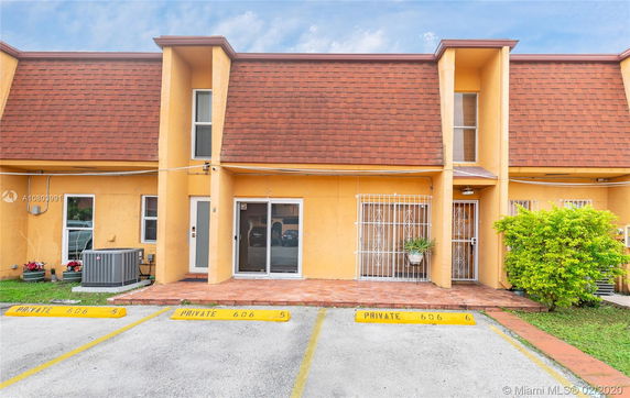 Front view of a two-story townhouse with yellow exterior and brown shingle roof.