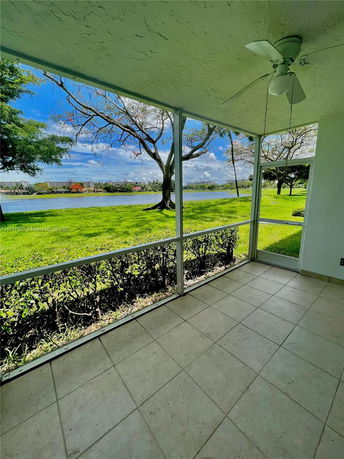 View from a covered patio overlooking a grassy area and a lake.