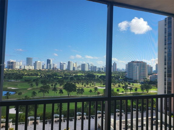 Panoramic view of a cityscape with high-rise buildings and a golf course visible from a balcony.