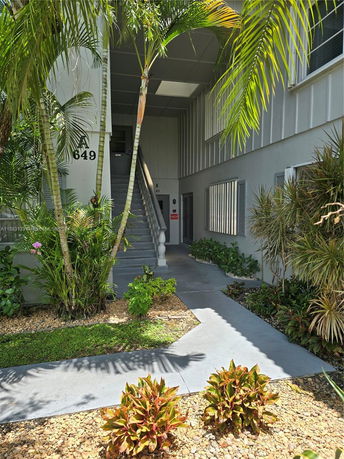 Front view of a building entrance with stairs and plants.