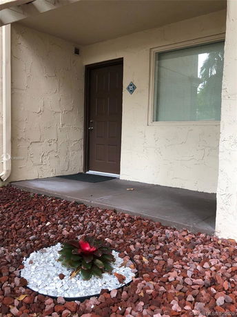 Front view of a house entrance with a brown door and a window.