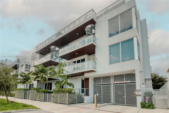 Front view of a modern multi-story building with glass balconies.