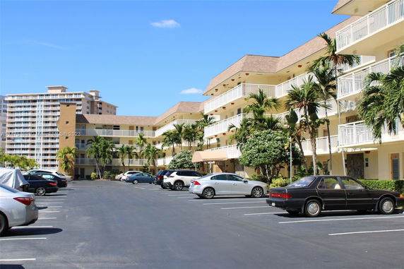 Outdoor parking area in front of a multi-story residential building with balconies.