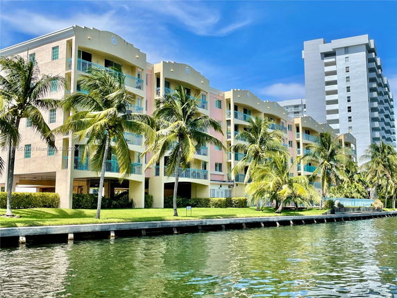 Front view of a multi-story building with balconies, adjacent to a waterway.