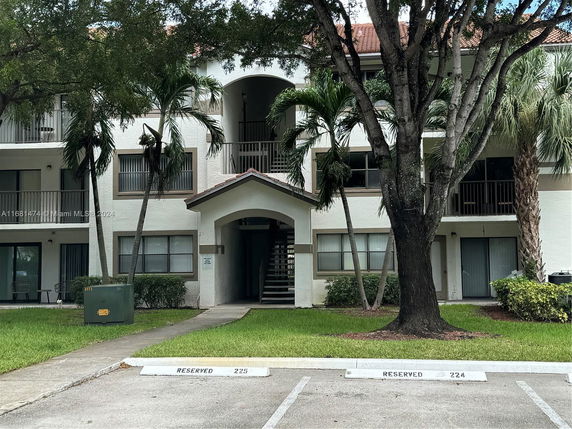Front view of a multi-story apartment building with reserved parking spaces.