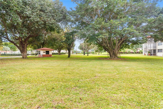 Grassy area with large trees and a small building