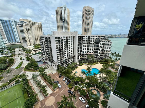 Panoramic view of a multi-story building complex with a pool and surrounding skyscrapers near a body of water.
